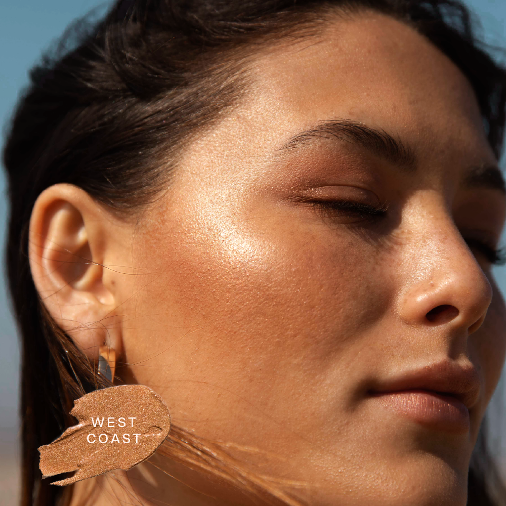 A close up of a model wearing Tower 28 Beauty's Bronzino™ Cream Bronzer in the shade West Coast