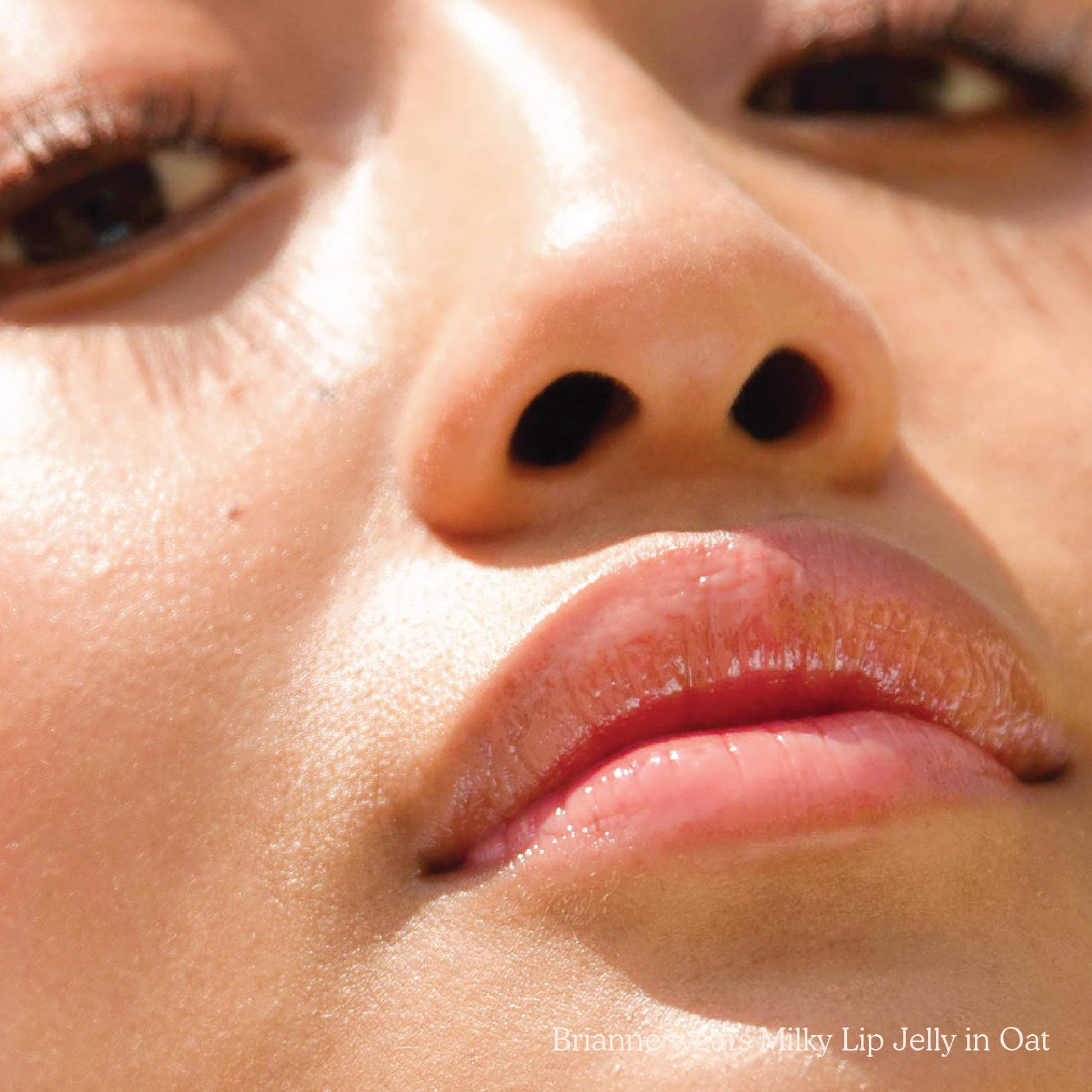 Closeup photo of a girl with very glossy lips, wearing the Tower 28 Beauty ShineOn Milky Lip Jelly shade in Oat (a milky peachy-pink)