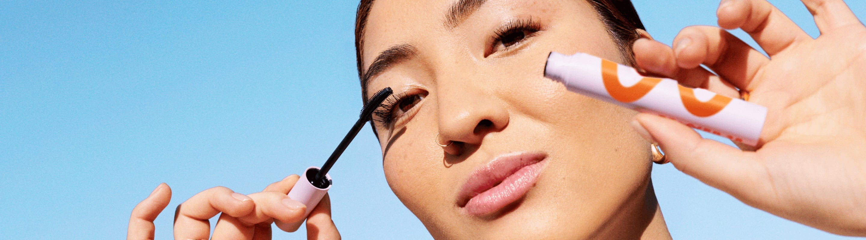 [A model holding up Tower 28 Beauty's MakeWaves Mascara and applying it on her lashes.]