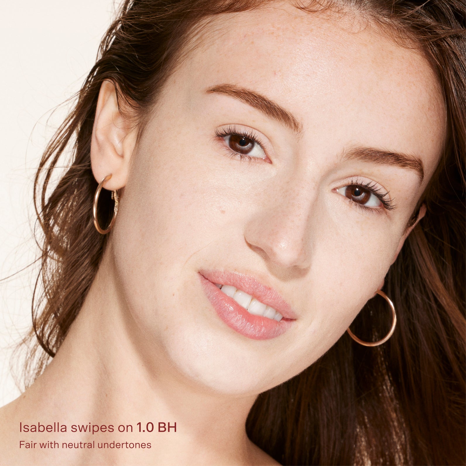 Close-up of a woman's face with brown hair and hoop earrings, wearing makeup. [1.0 BH]