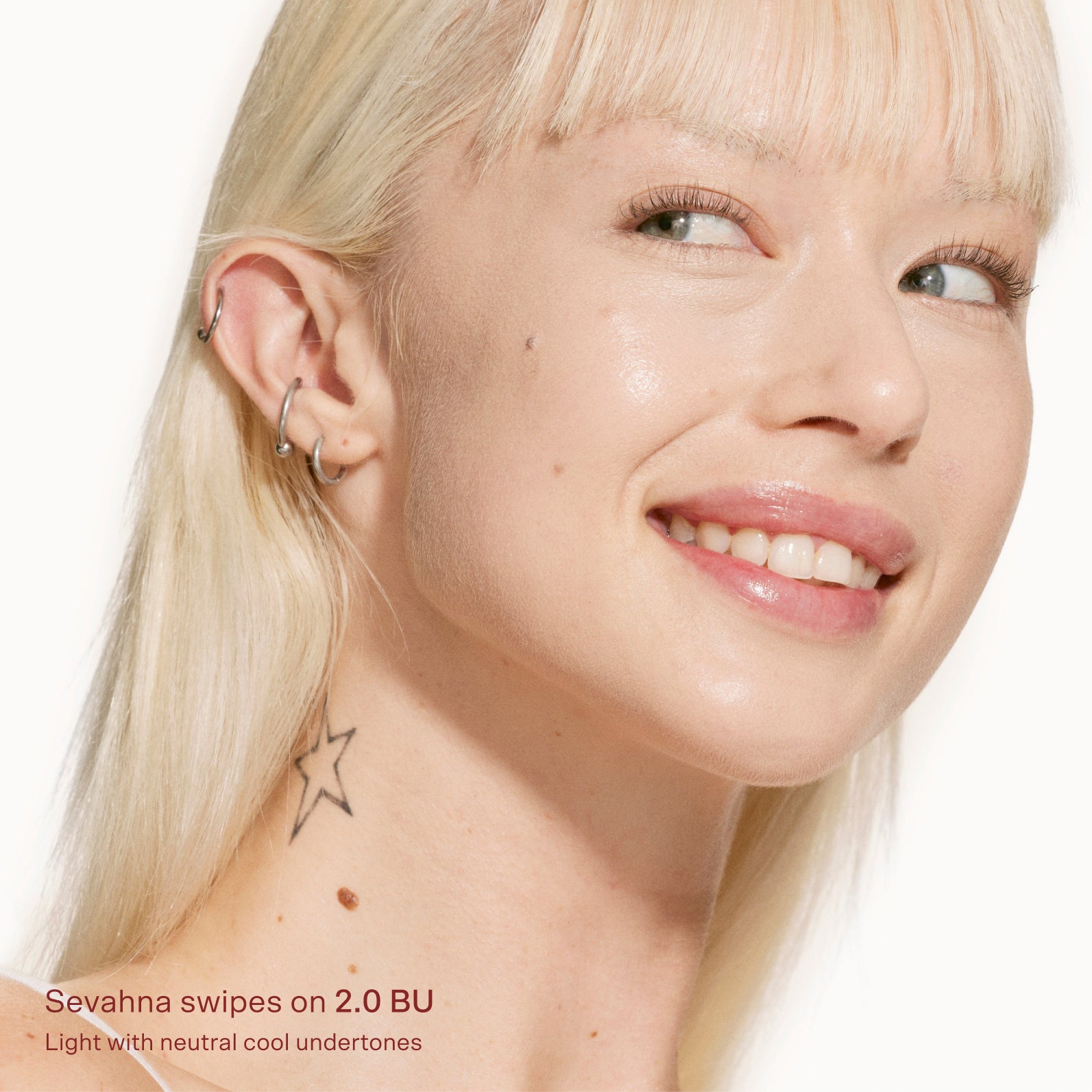 Close-up of a woman with blonde hair and visible ear, wearing earrings on a white background. [2.0 BU]