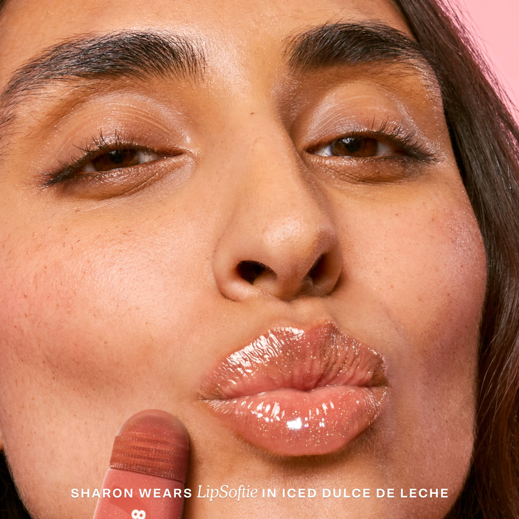 Close-up of a person wearing lip gloss with text indicating product name and color. [Shared]