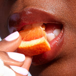 A close up of a model wearing Tower 28 Beauty's LipSoftie™ Lip Treatment in Blood Orange Vanilla on her lips. [Blood Orange Vanilla]