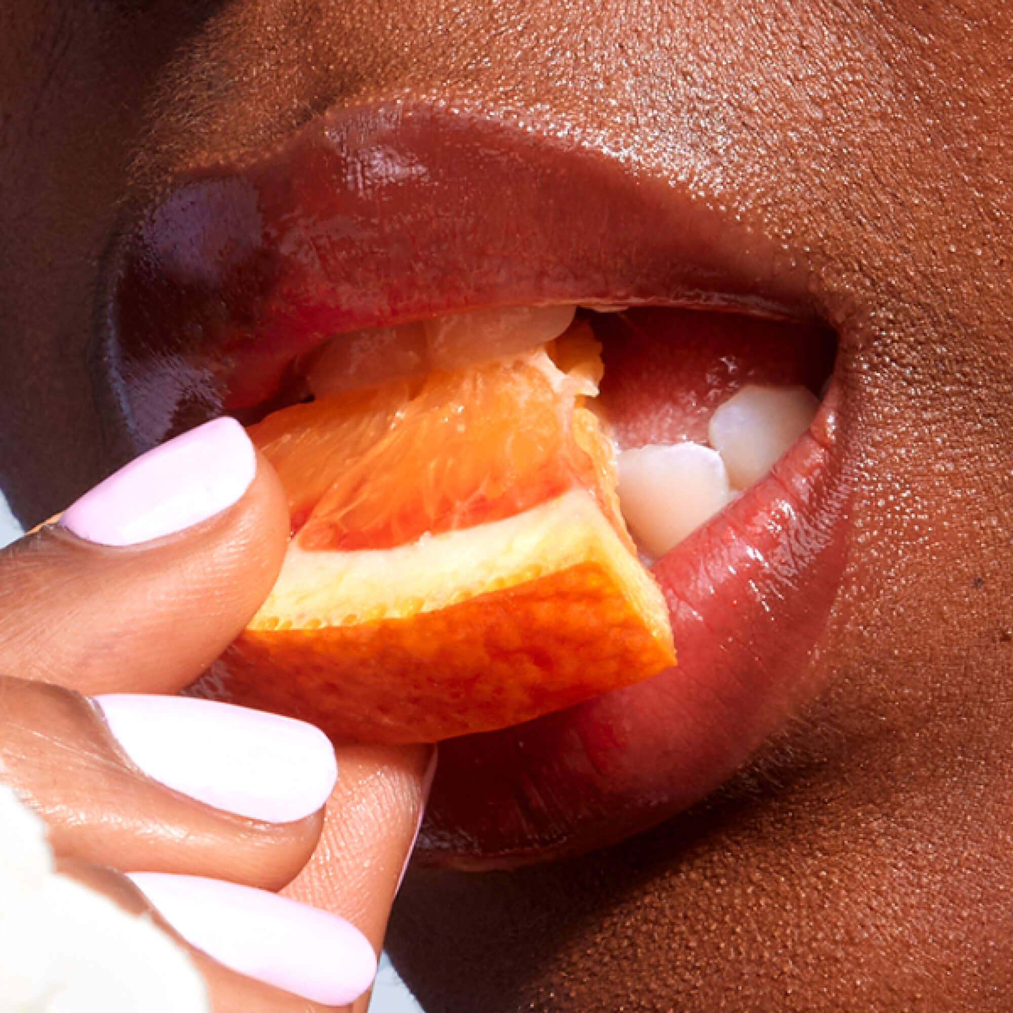 A close up of a model wearing Tower 28 Beauty's LipSoftie™ Lip Treatment in Blood Orange Vanilla on her lips. [Blood Orange Vanilla]