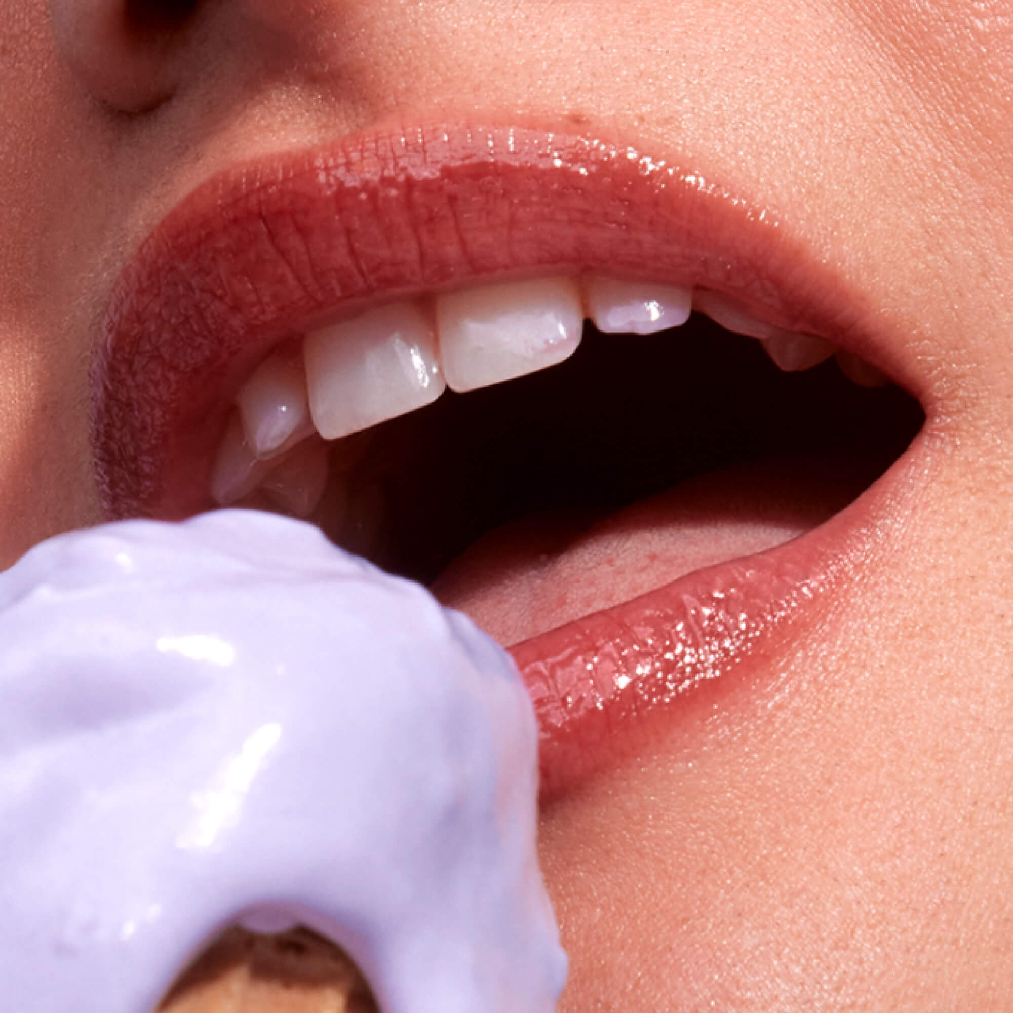 A close up of a model wearing Tower 28 Beauty's LipSoftie™ Lip Treatment in Ube Vanilla on her lips. [Ube Vanilla]