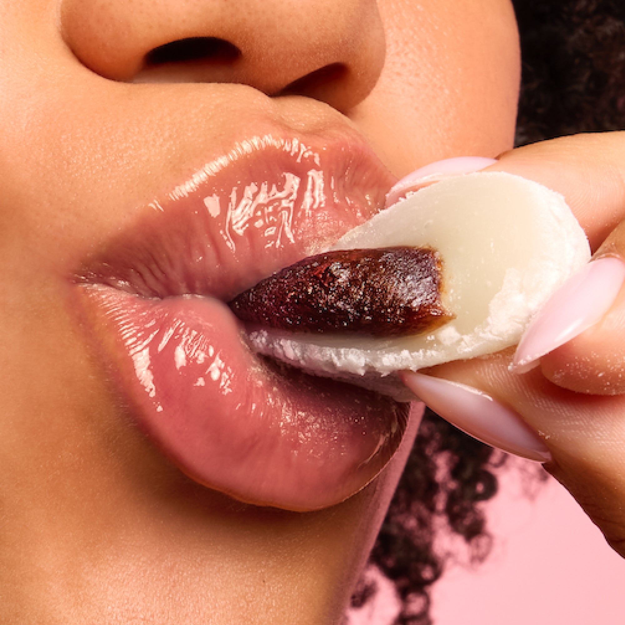 A close up of a model wearing Tower 28 Beauty's LipSoftie® Lip Treatment in Red Bean Mochi on her lips. [Red Bean Mochi]