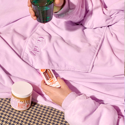 [Shared: A model lounging in Tower 28 Beauty x Comfy® Originals comfy alongside her Tower 28 Beauty x Deux Cookie Butter Drip and Lip Drip Duo, which features two full-sized ShineOn Lip Jelly.]