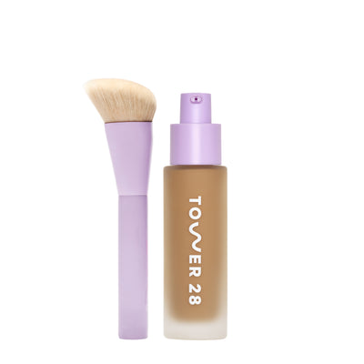 [shared] Tower 28 liquid foundation bottle in a frosted beige glass with a lavender pump, shown next to a matching lavender makeup brush with beige bristles on a white background.