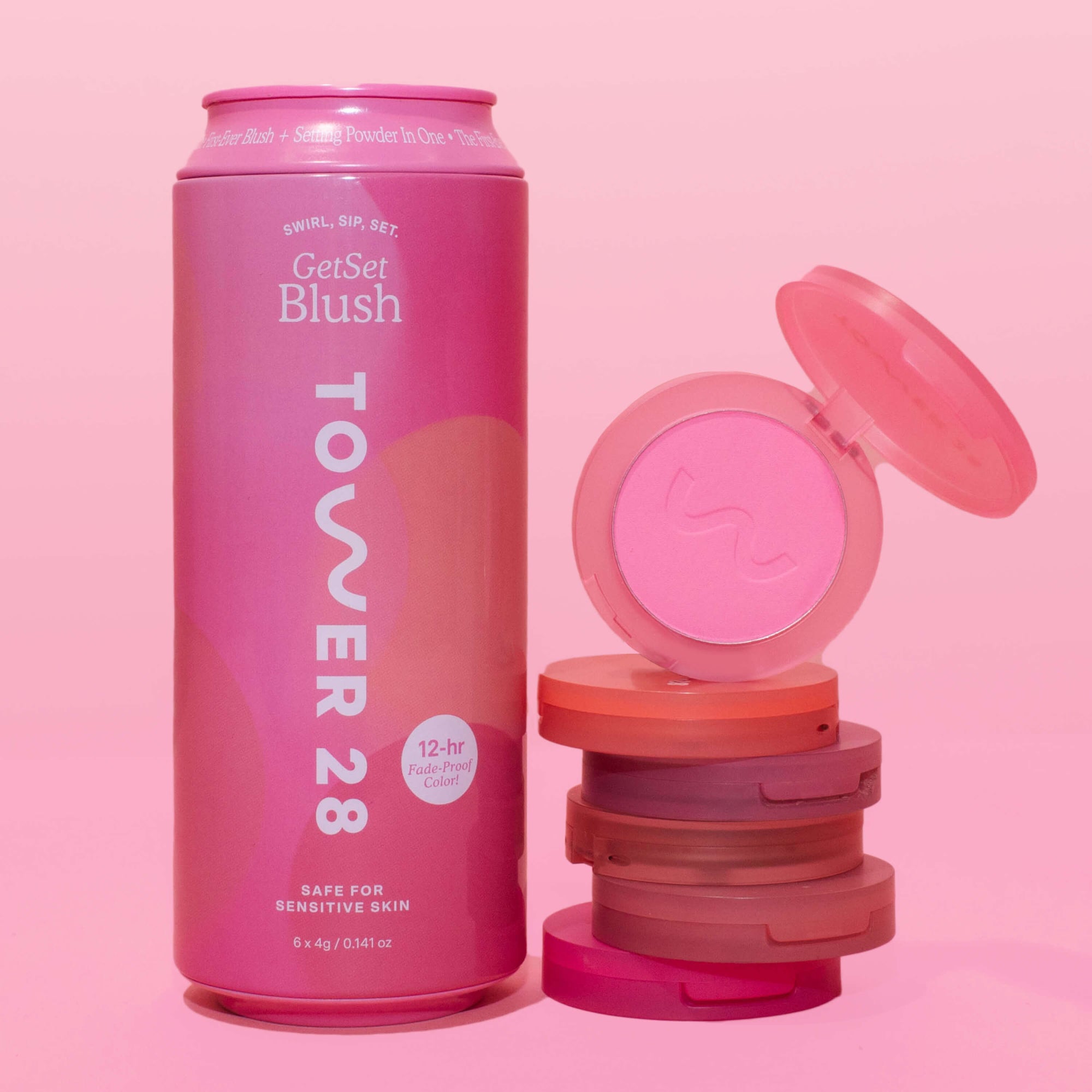 A Tower 28 Beauty can-shaped box is displayed next to a stack of GetSet Powder Blush compacts. The top compact is open, featuring the bright pink shade Malibu Cooler. [GetSet Powder Blush Gift Set]