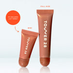 Two Tower 28 lip gloss tubes, one full-size and one mini, on a light gray background. [Lil’ Softies Lip Treatment Set]