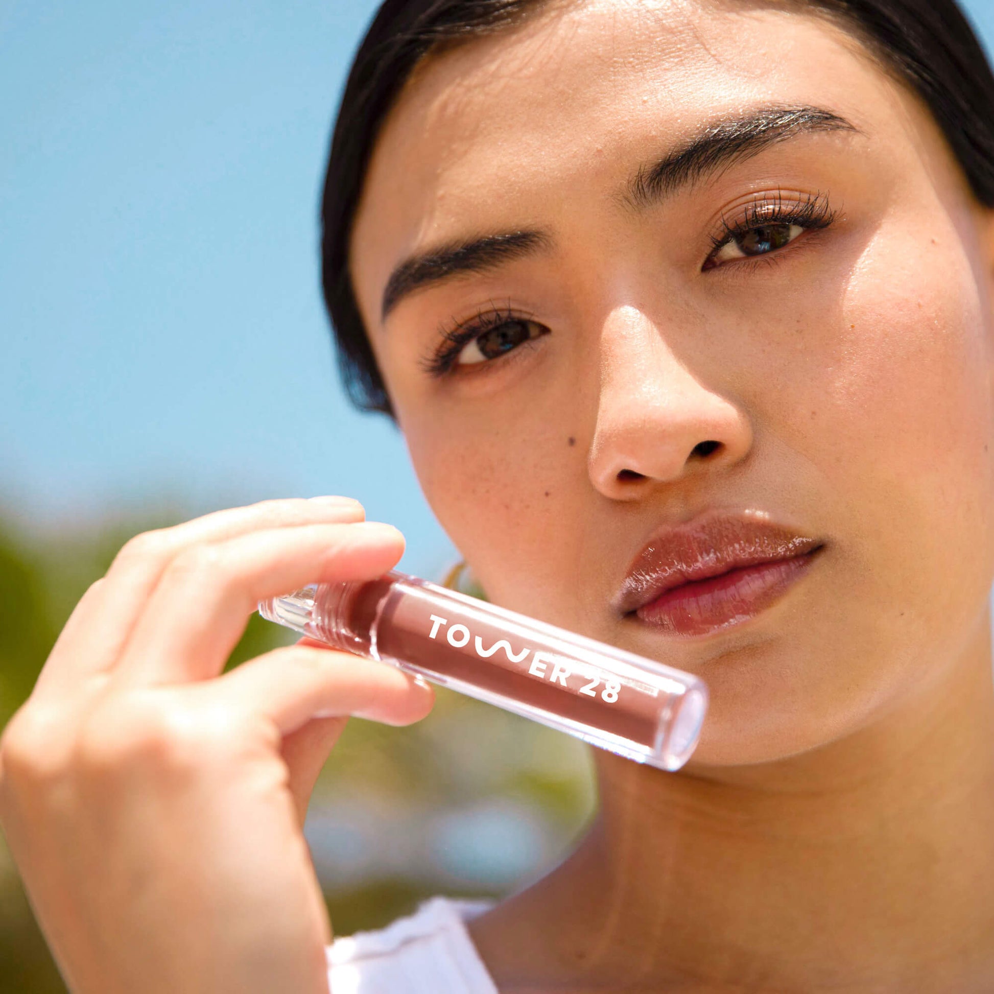 A model wearing the Tower 28 Beauty ShineOn Lip Jelly in the shade Almond on her lips