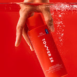 Hand holding a red bottle labeled 'Tower 28' underwater with a red background [Shared]