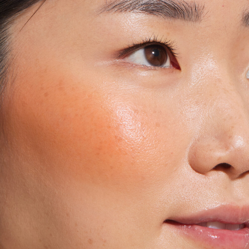 A close up of a model with Tower 28 Beauty's BeachPlease Cream Blush in Golden Hour on her face.