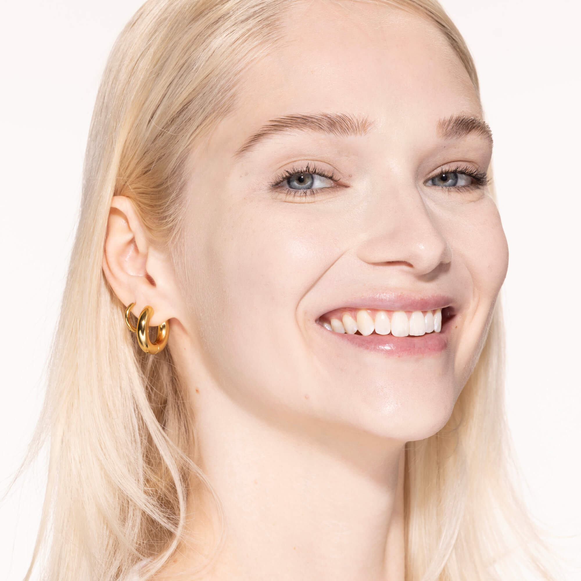 A person wearing Tower 28 Beauty's Swipe Serum Concealer in shade 1.0 BH, shown with a smooth, even complexion and radiant finish. [1.0 BH]