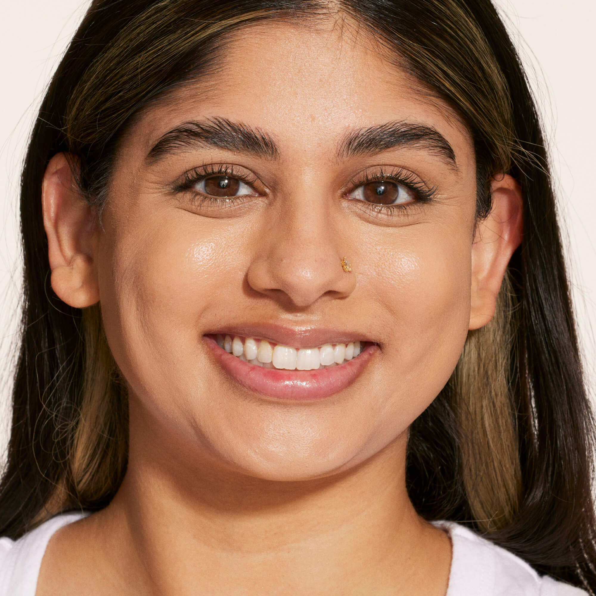 A person's face before and after using Tower 28 Beauty's Swipe Serum Concealer in shade 10.0 NOHO, shown with visibly brightened under eyes, evened skin tone, and a radiant finish. [10.0 NOHO]