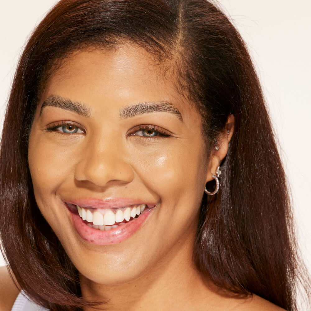 A person shown wearing Tower 28 Beauty's Swipe Serum Concealer in shade 12.0 PALI, with an even skin tone, smoother complexion, and a soft natural finish. [12.0 PALI]