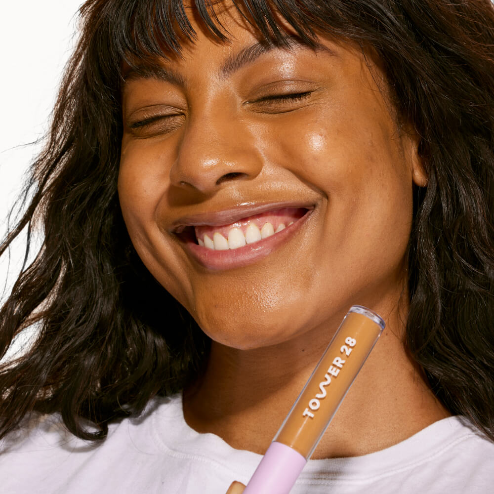 A person holding Tower 28 Beauty's Swipe Serum Concealer in shade 14.0 PV, shown with a smooth, even complexion and natural skin-like finish. [14.0 PV]