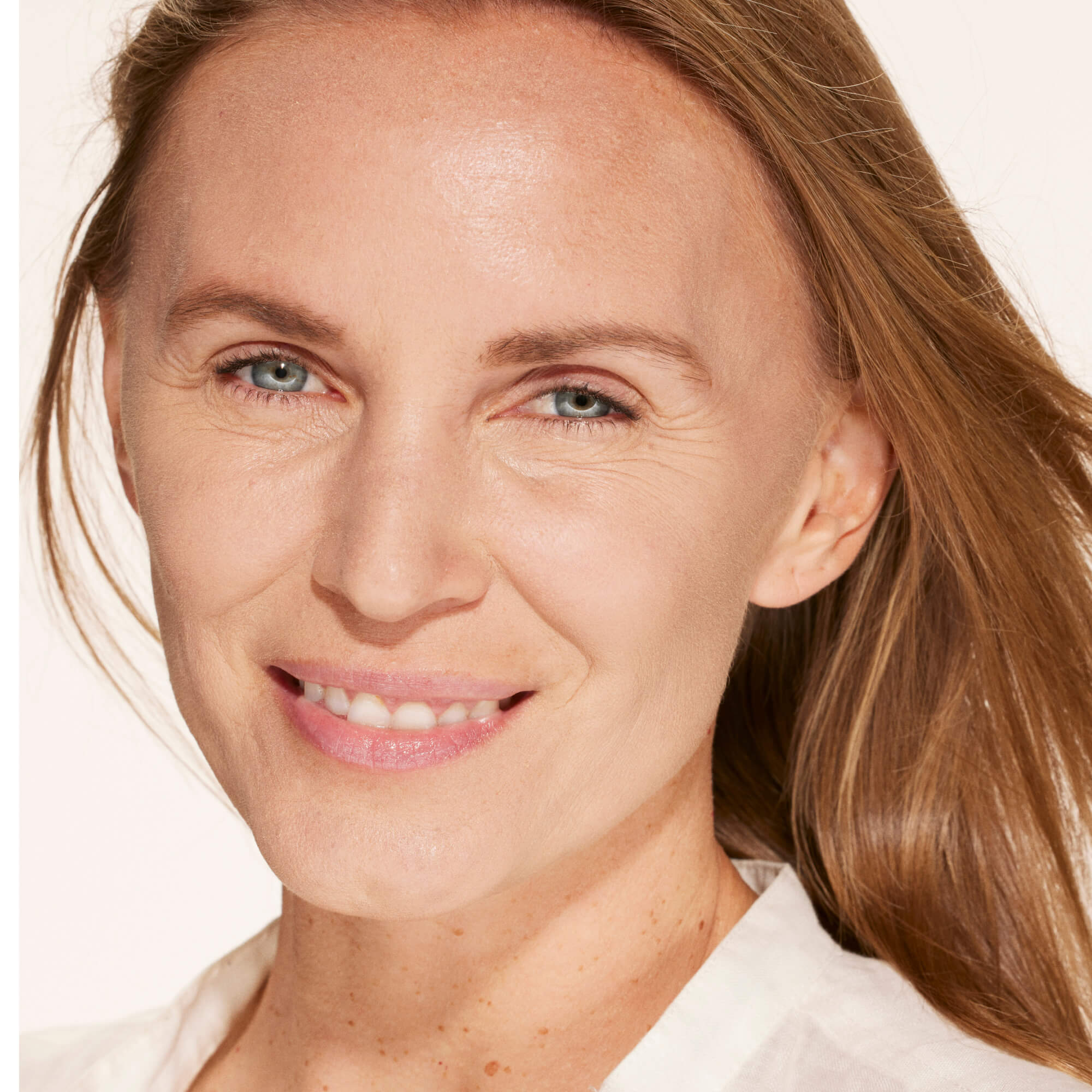 A person wearing Tower 28 Beauty's Swipe Serum Concealer in shade 6.0 IE, shown with a brightened, even complexion and natural finish. [6.0 IE]