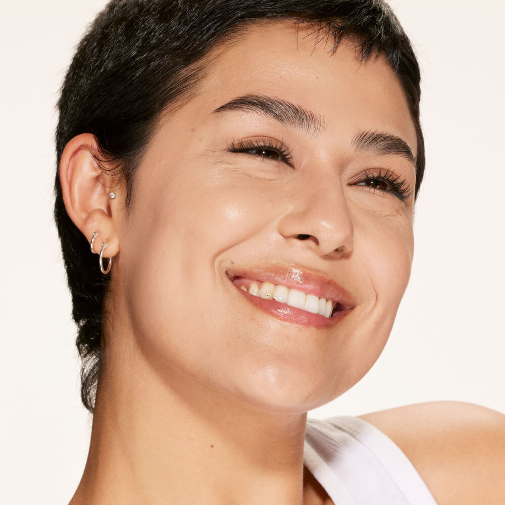 A person wearing Tower 28 Beauty's Swipe Serum Concealer in shade 7.0 KTOWN, shown with an even complexion, softened texture, and natural skin finish. [7.0 KTOWN]