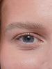 A close up of a model applying the Tower 28 Beauty MakeWaves Mascara on their lashes and then showing the mascara wand in detail.