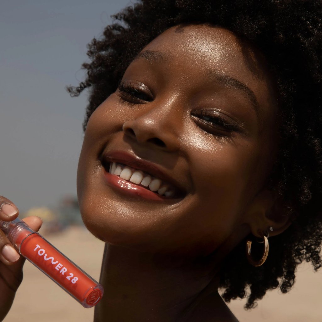 A model wearing the Tower 28 Beauty ShineOn Lip Jelly in the shade Fire on her lips