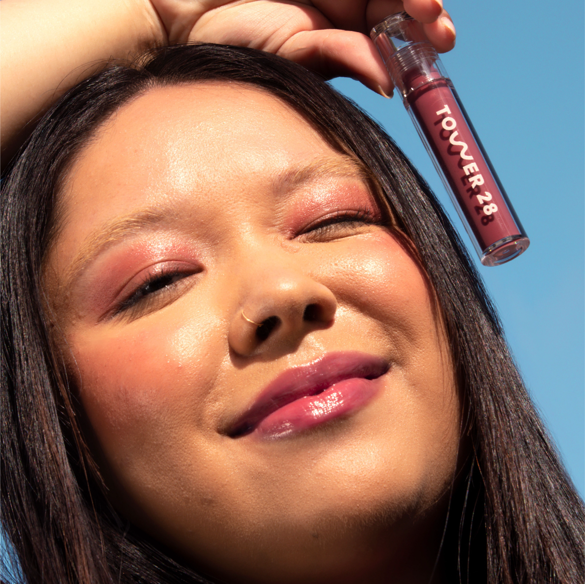 A model wearing the Tower 28 Beauty ShineOn Lip Jelly in the shade Sesame on her lips